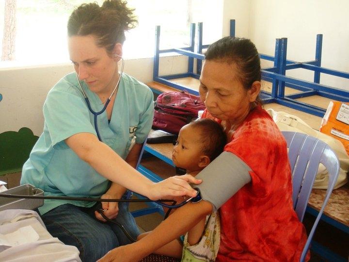 Pasante de Medicina en Camboya realizando chequeo de salud. Una mujer local y su hijo reciben tratamiento en una de nuestras pasantías de Medicina en Camboya.